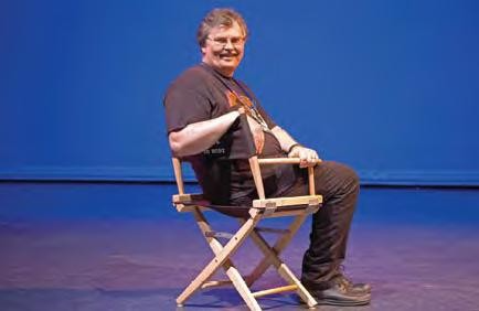 A man sits and looks back from a director's chair.