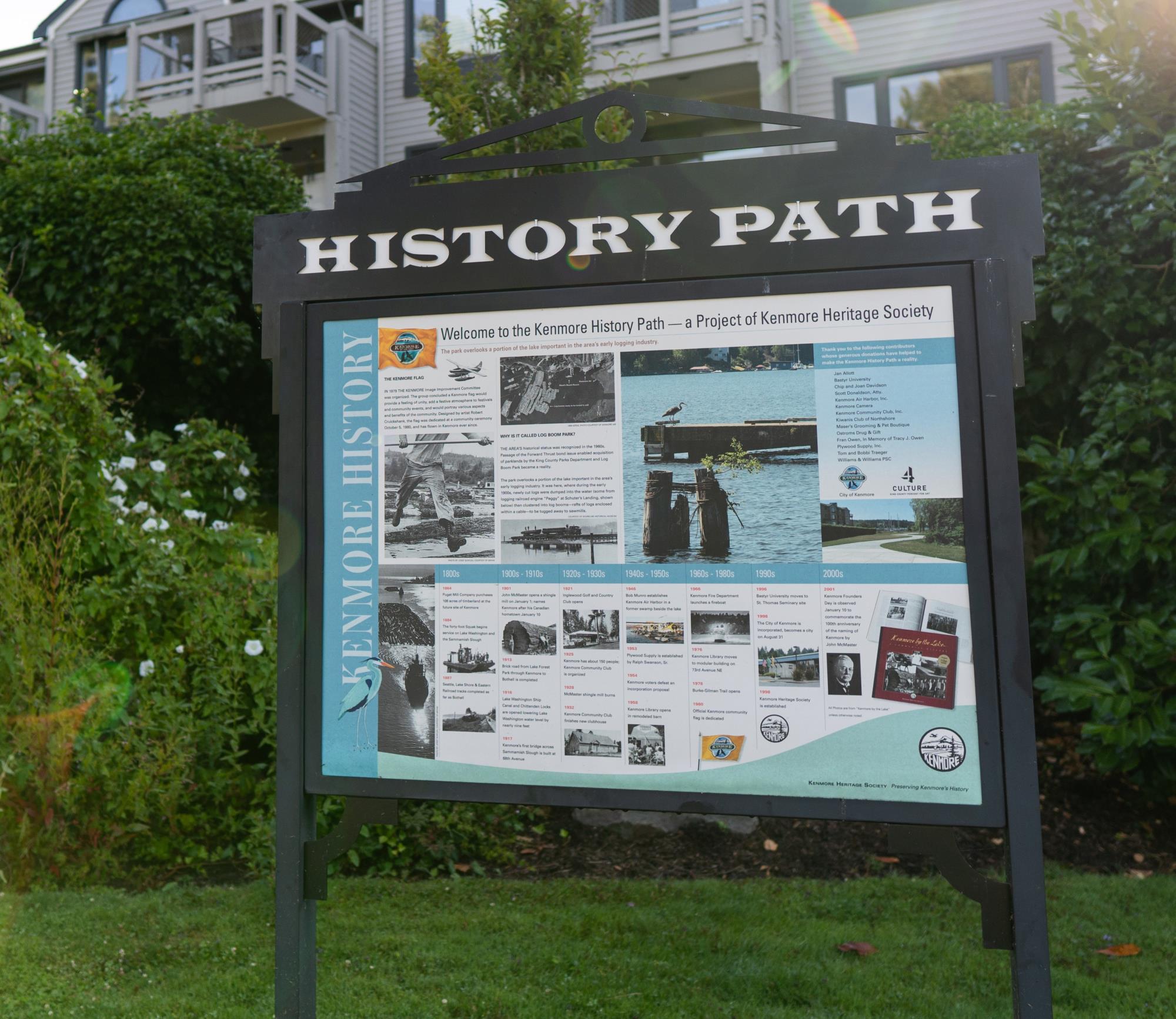 Entry sign along the history path at Log Boom Park. The header of the sign reads, "Welcome to the Kenmore History Path - a project of the Kenmore Heritage Society. Underneath, a timeline on the founding of Kenmore. 