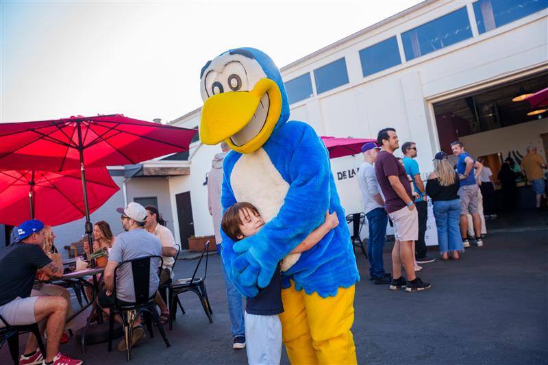 Hank Heron gives a young resident a hug as community members eat and drink outside of De La Soil restaurant.